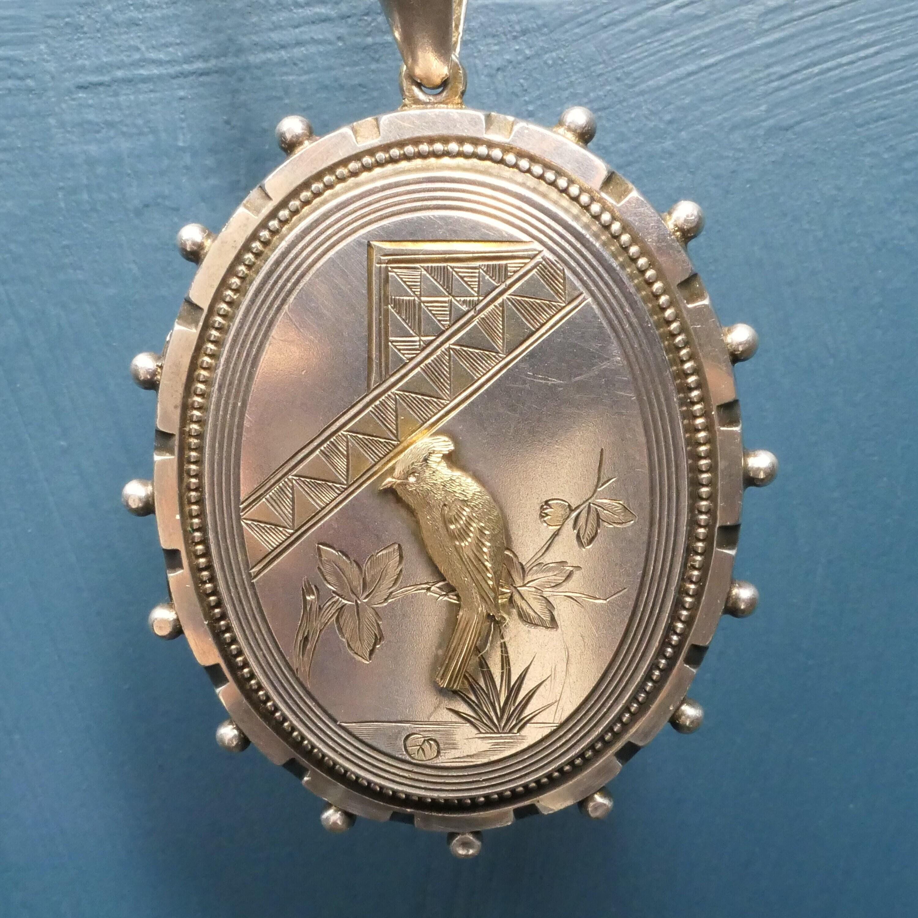 Victorian sterling silver engraved locket with gold bird motif and beaded oval border