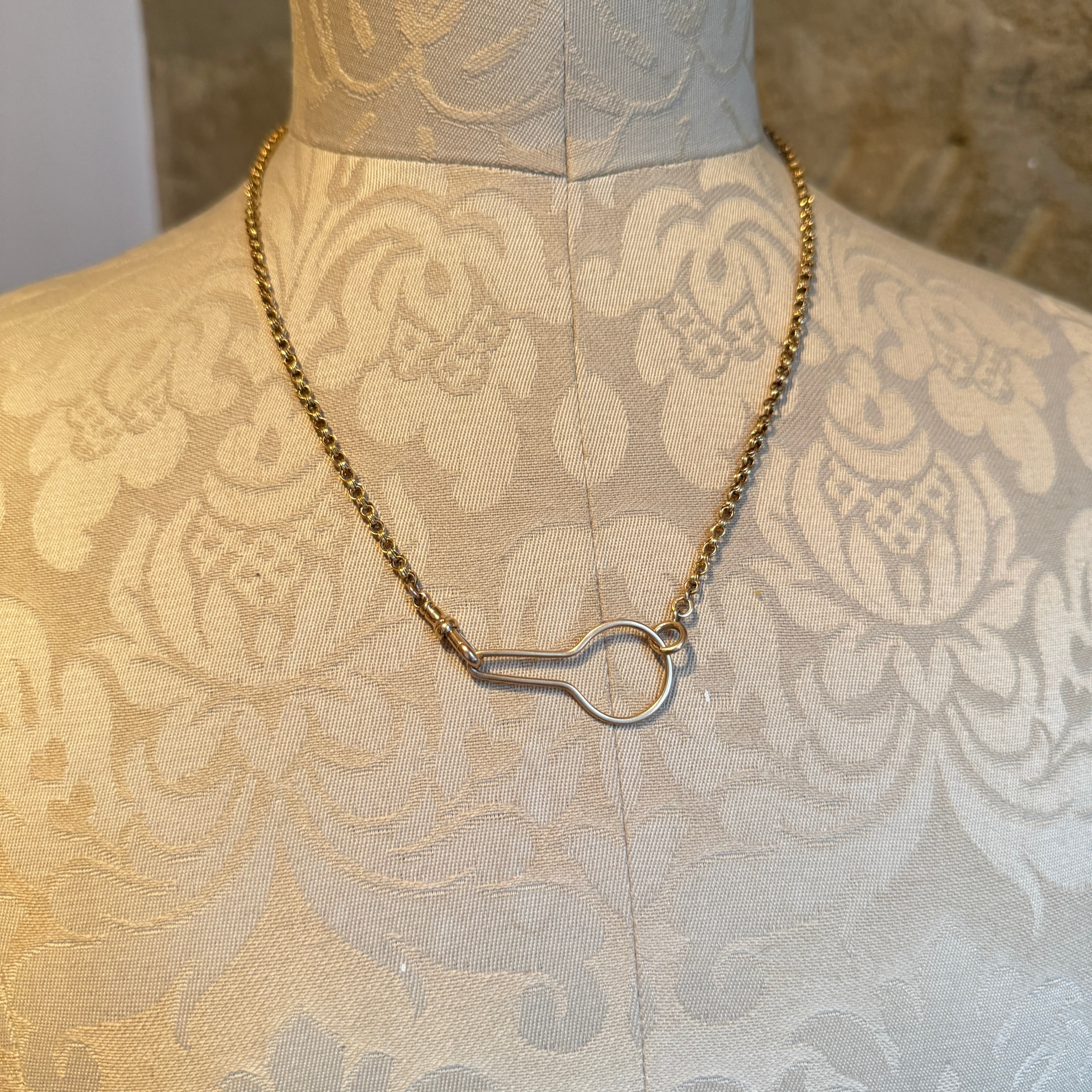 Necklace with a unique clasp on a mannequin wearing a patterned garment.