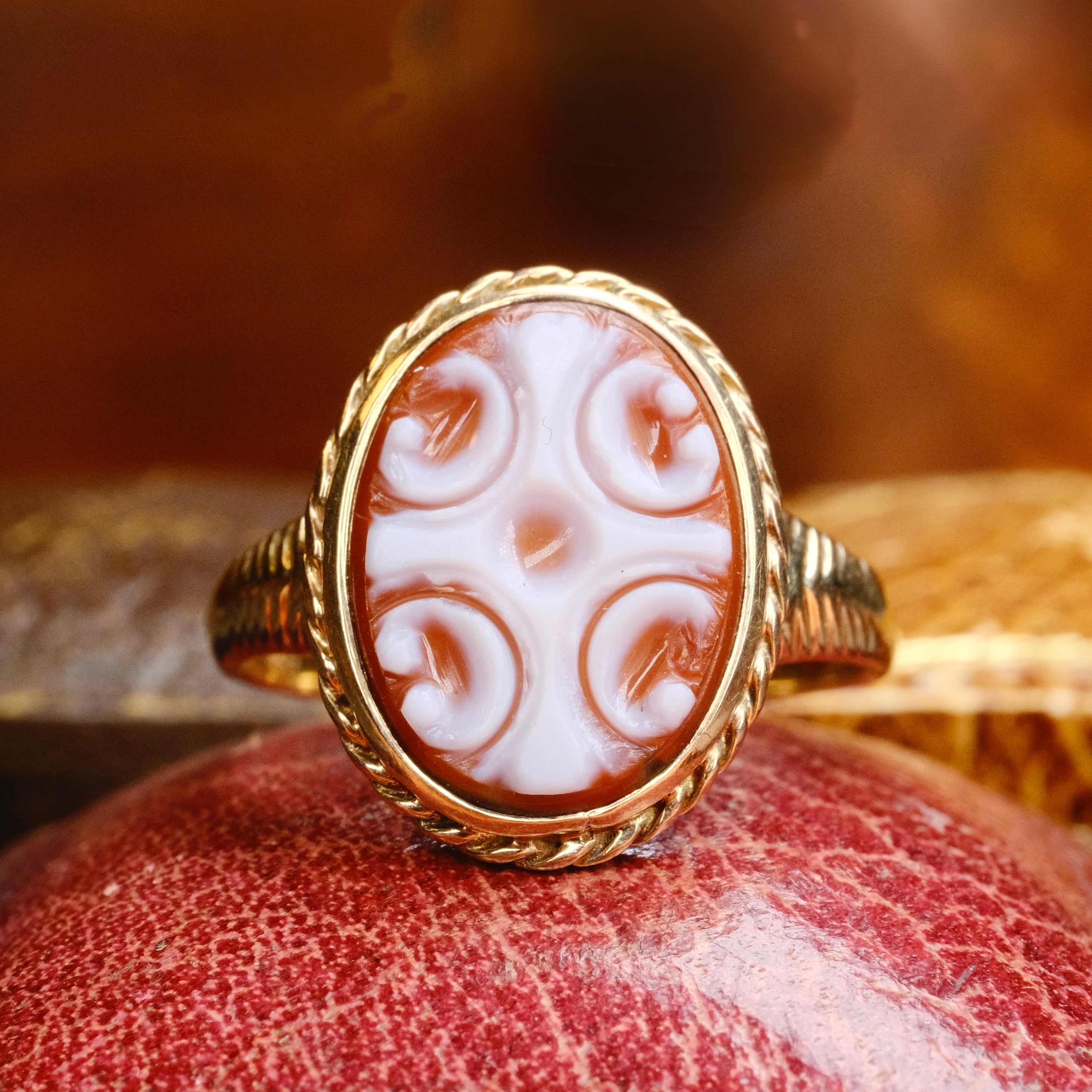 Gold ring with a white cameo on a textured surface