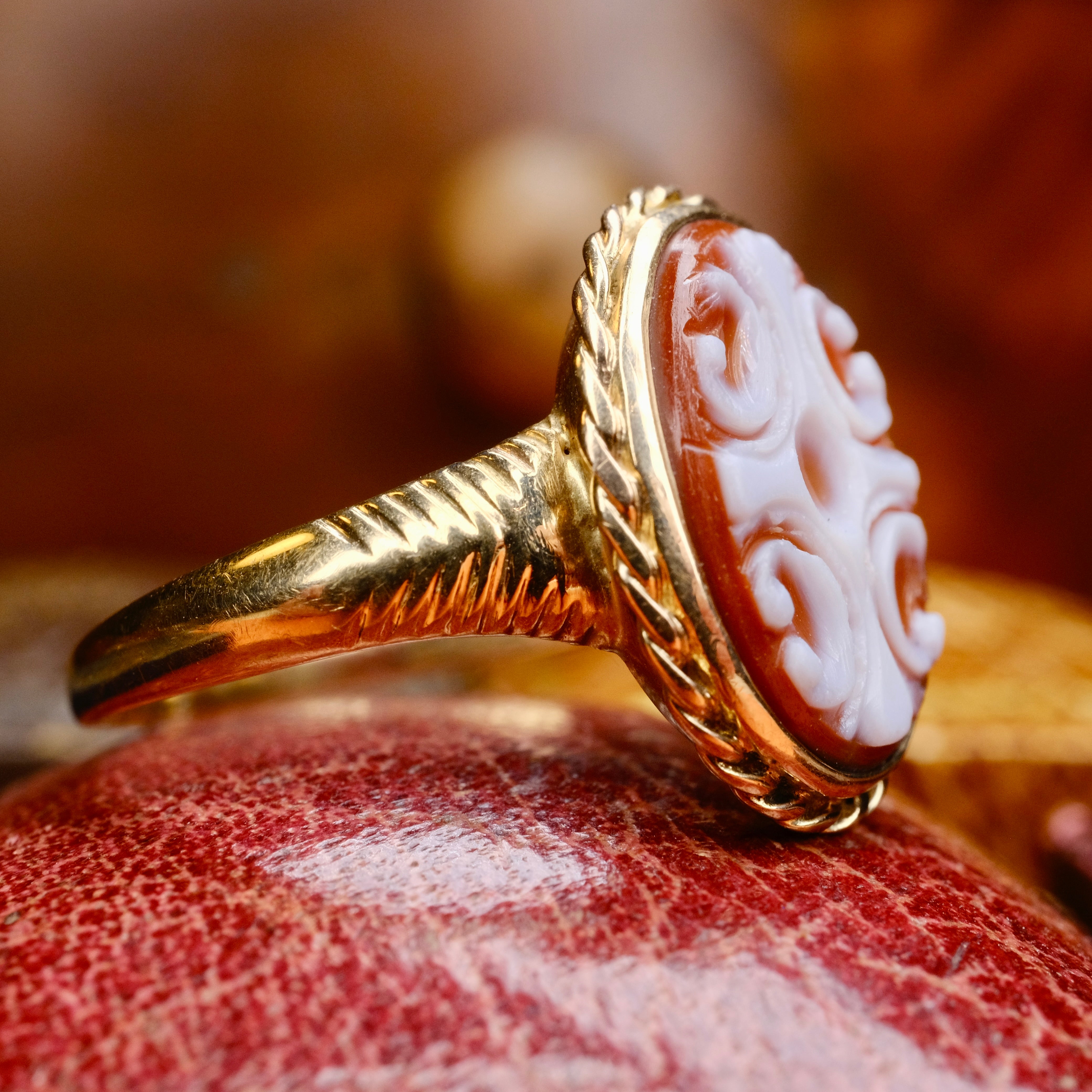 Gold ring with a detailed stone on a textured surface